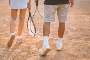 young couple playing tennis at the court feet close up