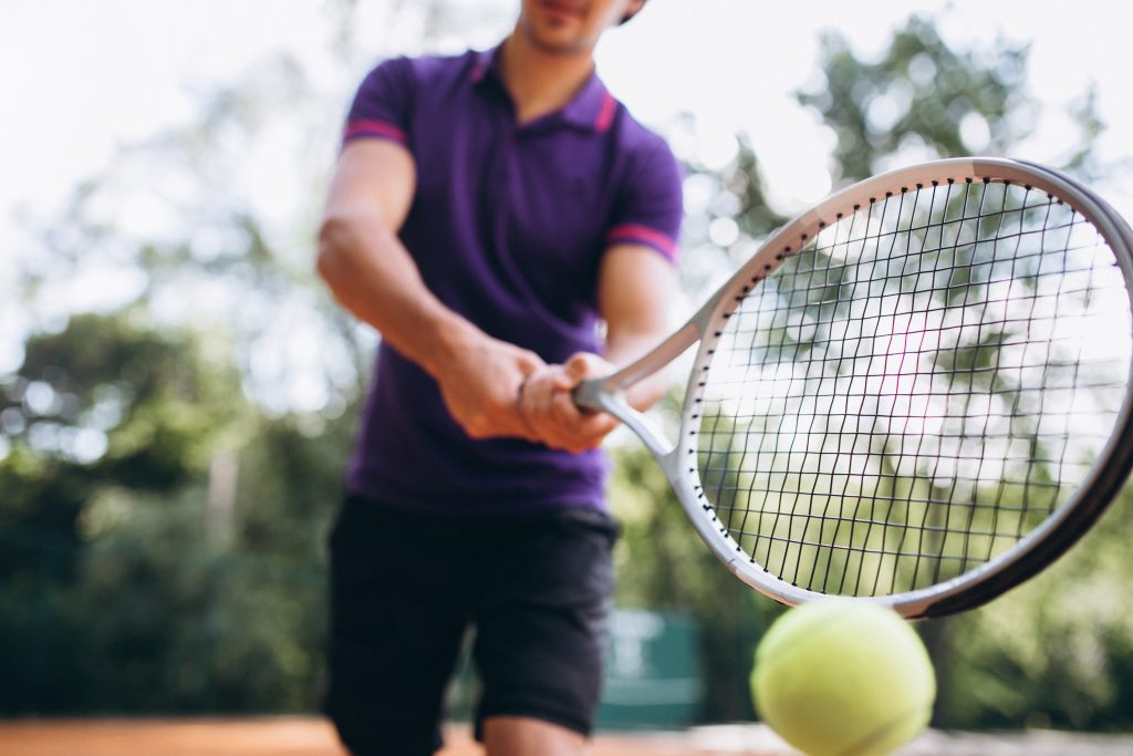 Tênis : O que é o Tênis de Quadra e quais os benefícios? Tudo sobre o esporte, como jogar e quais os melhores equipamentos - Blog da Bola de Tênis Delivery - young man tennis player at the court tennis racket close up